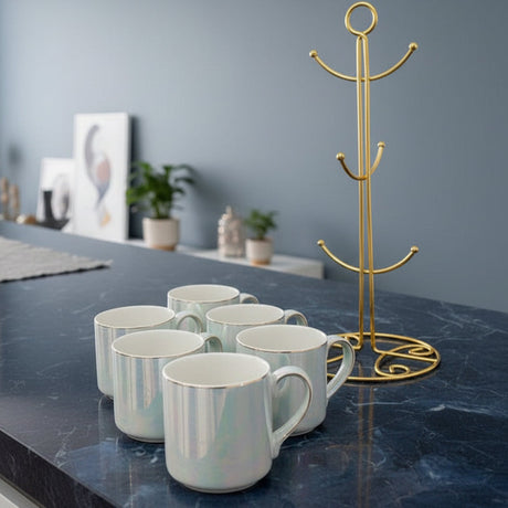 Six white iridescent ceramic mugs with gold rims on a navy marble counter