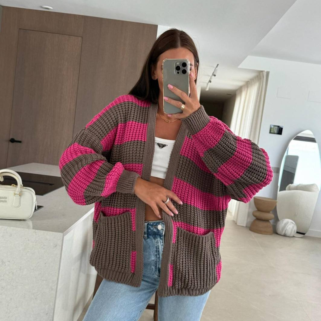Taupe and fuchsia striped cardigan, one hand resting on the pocket, styled at home