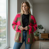 Oversized striped cardigan in fuchsia, standing by a bright window