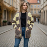 Yellow and taupe striped cardigan worn open over a black tee on a cobbled street