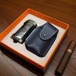 Cigar lighter and leather case in an open orange box on a wooden surface