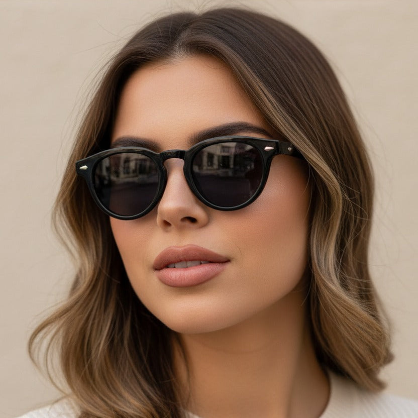 Woman wearing black round-shaped sunglasses with a neutral background