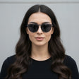 Woman wearing classic black sunglasses against a grey background