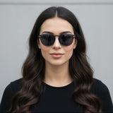Woman wearing classic black sunglasses against a grey background