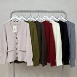 Button front knit cardigans on a rail, the beige one in front with its swing tag