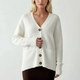 White knit cardigan buttoned up with front pockets and folded ribbed cuffs