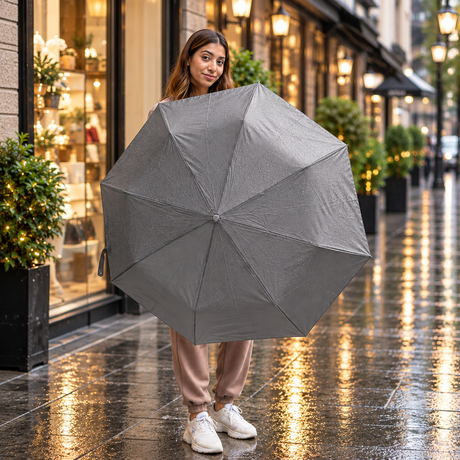 Woman on a rainy street holding open a plain grey folding umbrella