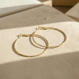 Classic gold hoop earrings on a beige surface