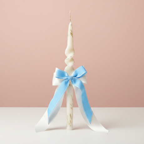 Twisted white candle with a blue and white satin bow