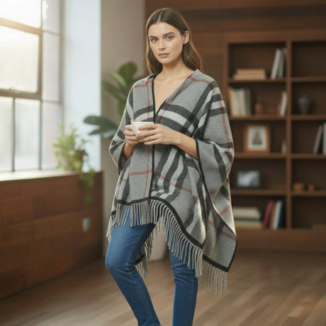 Woman wearing a classic plaid puncho in a cozy room with bookshelves and a window