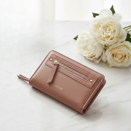 Pink wallet with gold accents on a white surface with white roses