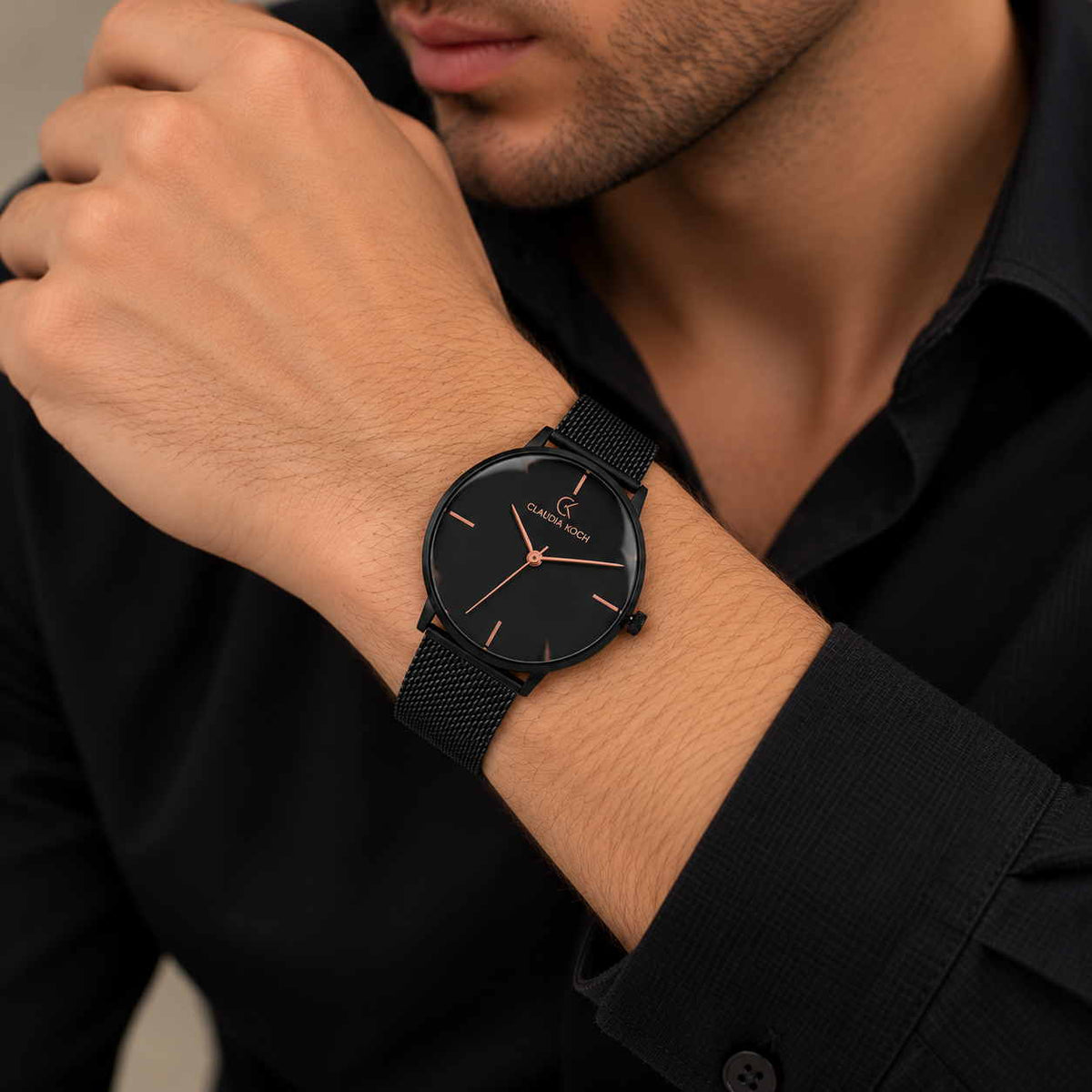 Minimal black mesh strap watch with rose gold hands worn on a man's wrist