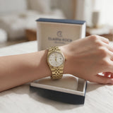 Gold fluted bezel watch with textured white dial worn in front of its box