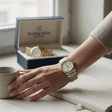 Two tone fluted bezel watch worn on a wrist resting by a coffee mug