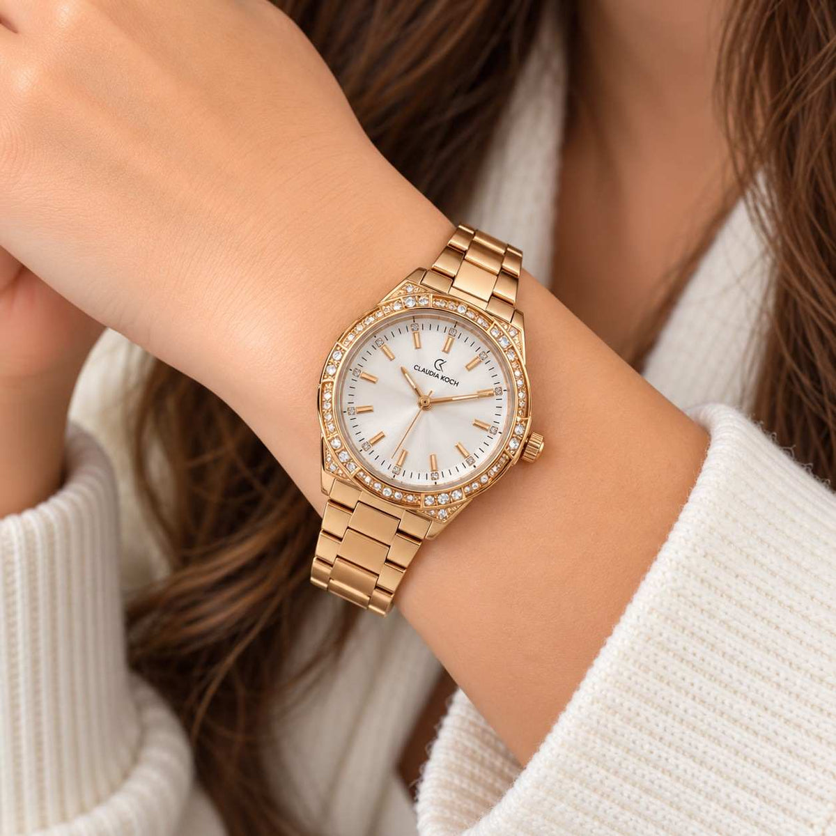 Gold watch with crystal set octagon bezel and white dial worn on the wrist