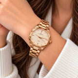 Rose gold watch with textured faceted dial worn with a cream knit sleeve