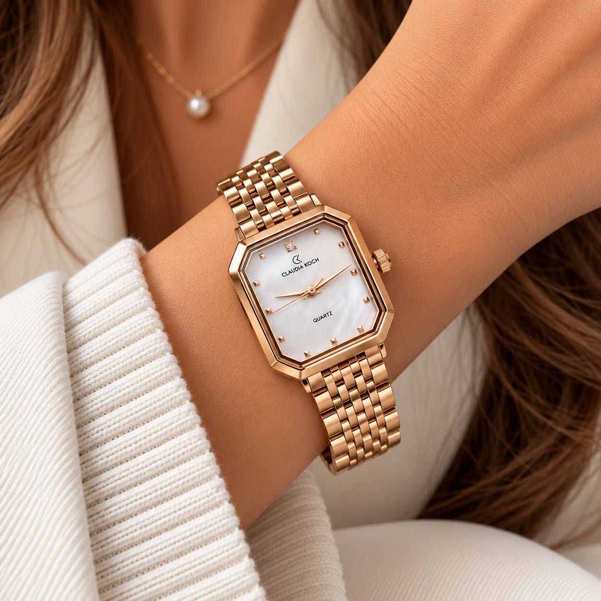 Rose gold rectangle watch with white pearl dial worn on the wrist