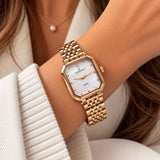 Rose gold rectangle watch with white pearl dial worn on the wrist