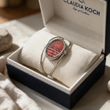 Red oval dial bangle watch with open silver wire cuff resting in a gift box