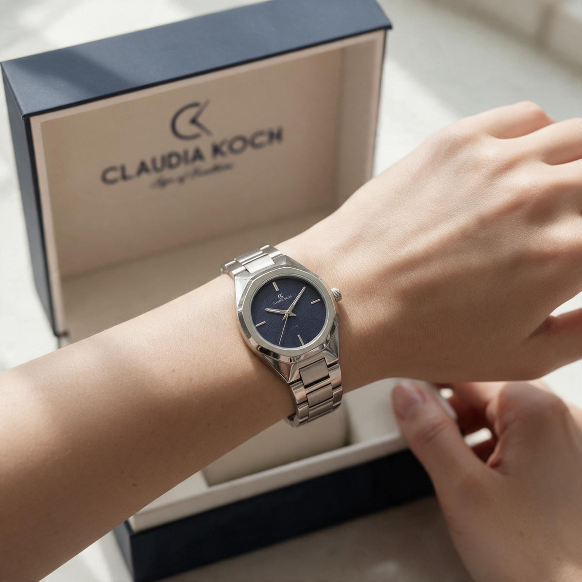 Silver steel watch with navy dial worn in front of an open gift box