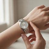 Silver steel watch with white dial being fastened on the wrist