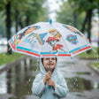 Child in a pale blue raincoat under a clear white umbrella printed with Paw Patrol