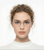 Woman wearing clear round sunglasses with a plain background