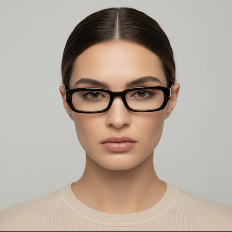 Woman wearing clear black totoise glasses against a grey background