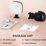 Selfie light, clip, charging cable and manual laid out on a pink surface
