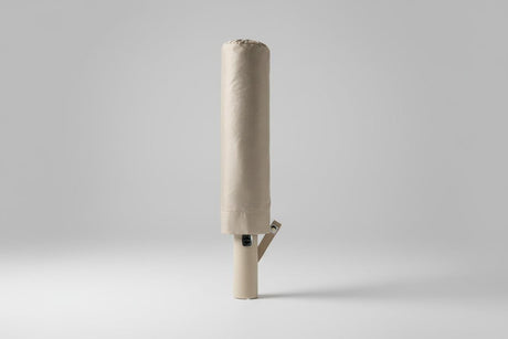 Foldable beige umbrella on a light grey background