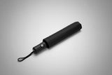 Closed black chic umbrella on a grey background