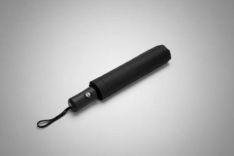 Closed black chic umbrella on a grey background
