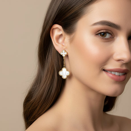 White clover-shaped earring worn by a woman on a beige background