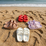 Set of red, brown, white, and pink sandals on a dark surface.