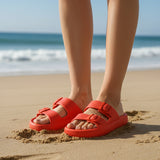 Person wearing red sandals on a beach with blurry background