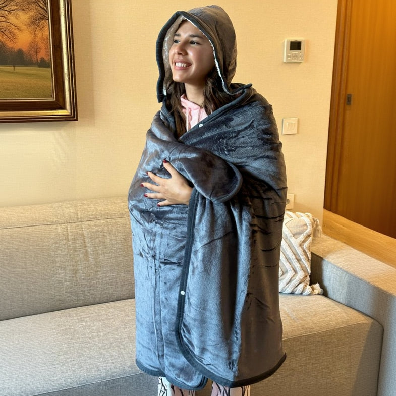 Person wrapped in a large gray hooded blanket in a living room.