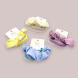 Four pastel satin knot hair ties in ivory, yellow, cornflower blue and mauve on soft fabric elastic bands