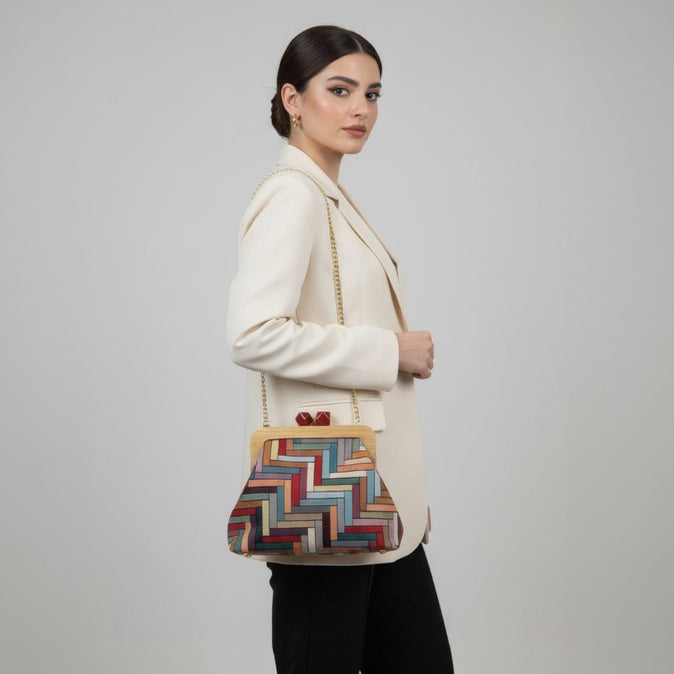 Woman holding a colorful handbag against a plain background