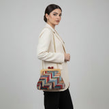 Woman holding a colorful handbag against a plain background