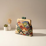 Green, red and yellow triangle weave handbag on a cream tabletop