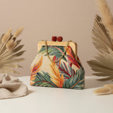 Cream tropical tapestry frame bag with green palm leaves and a coral clasp