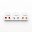 Three pairs of round solitaire stud earrings in red, clear and champagne