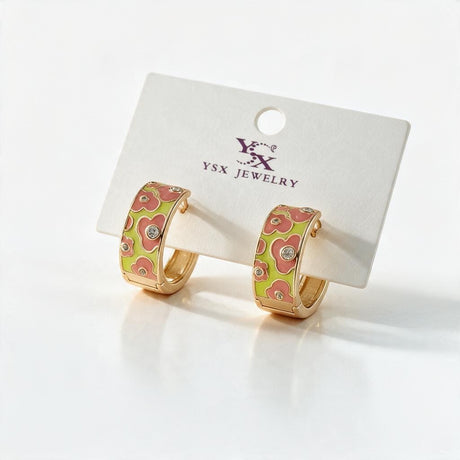Pair of coral and lime floral enamel gold tone huggie hoops on a white display card