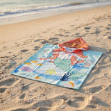 Aqua mermaid poncho towel with an orange haired mermaid, crab and octopus flat lay on sand