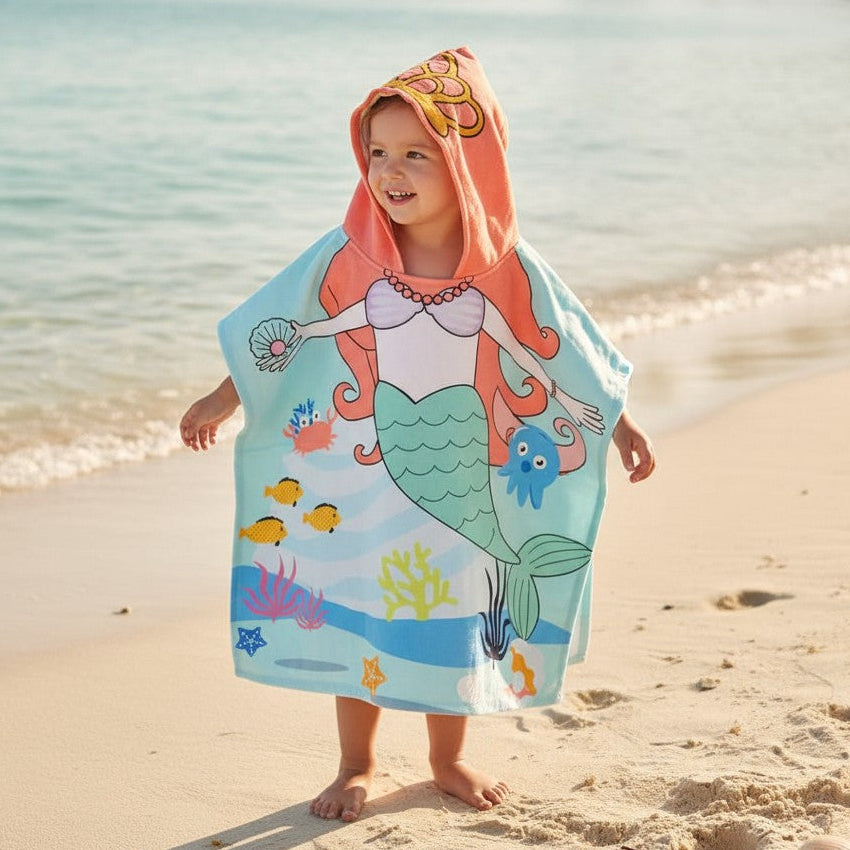 Girl wearing a pale aqua mermaid poncho towel with a coral hood and gold shell motif