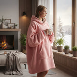 Pink hooded blanket worn standing beside a lit fireplace on a winter morning