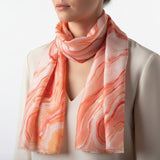 Person wearing a pink and orange marbled scarf on a plain background