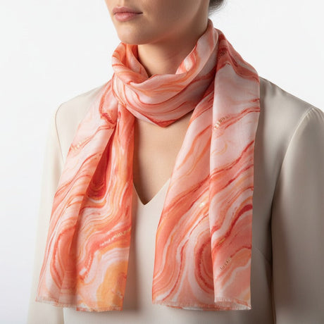 Person wearing a pink and orange marbled scarf on a plain background