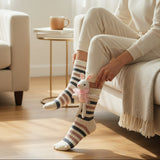 Woman in cream loungewear adjusting the bunny socks on a sofa
