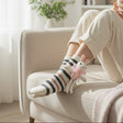 Striped plush socks with a pink bunny charm at the ankle, feet up on a chair